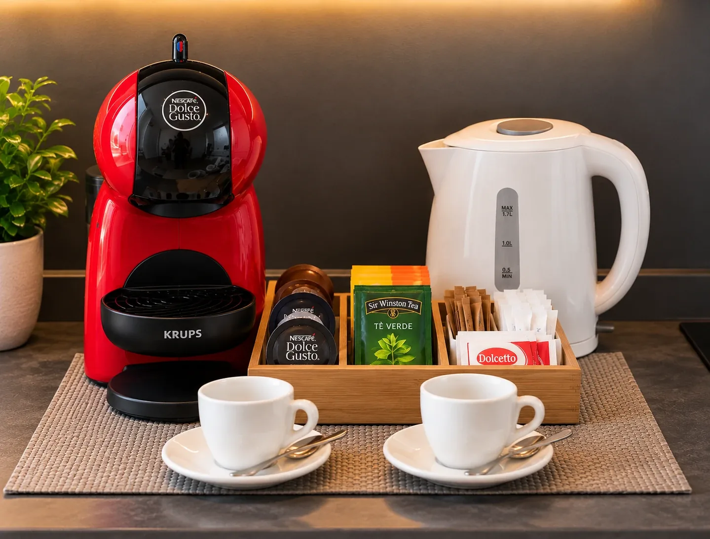 Angolo cortesia: macchinetta del caffè con capsule, bollitore, bustine di tè, zucchero e acqua